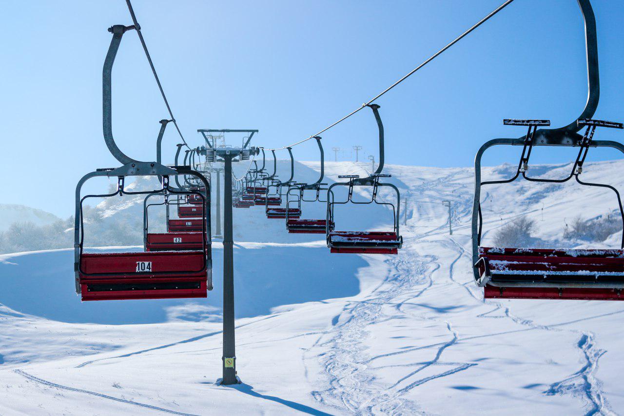 a ski lift with red chairs and snow